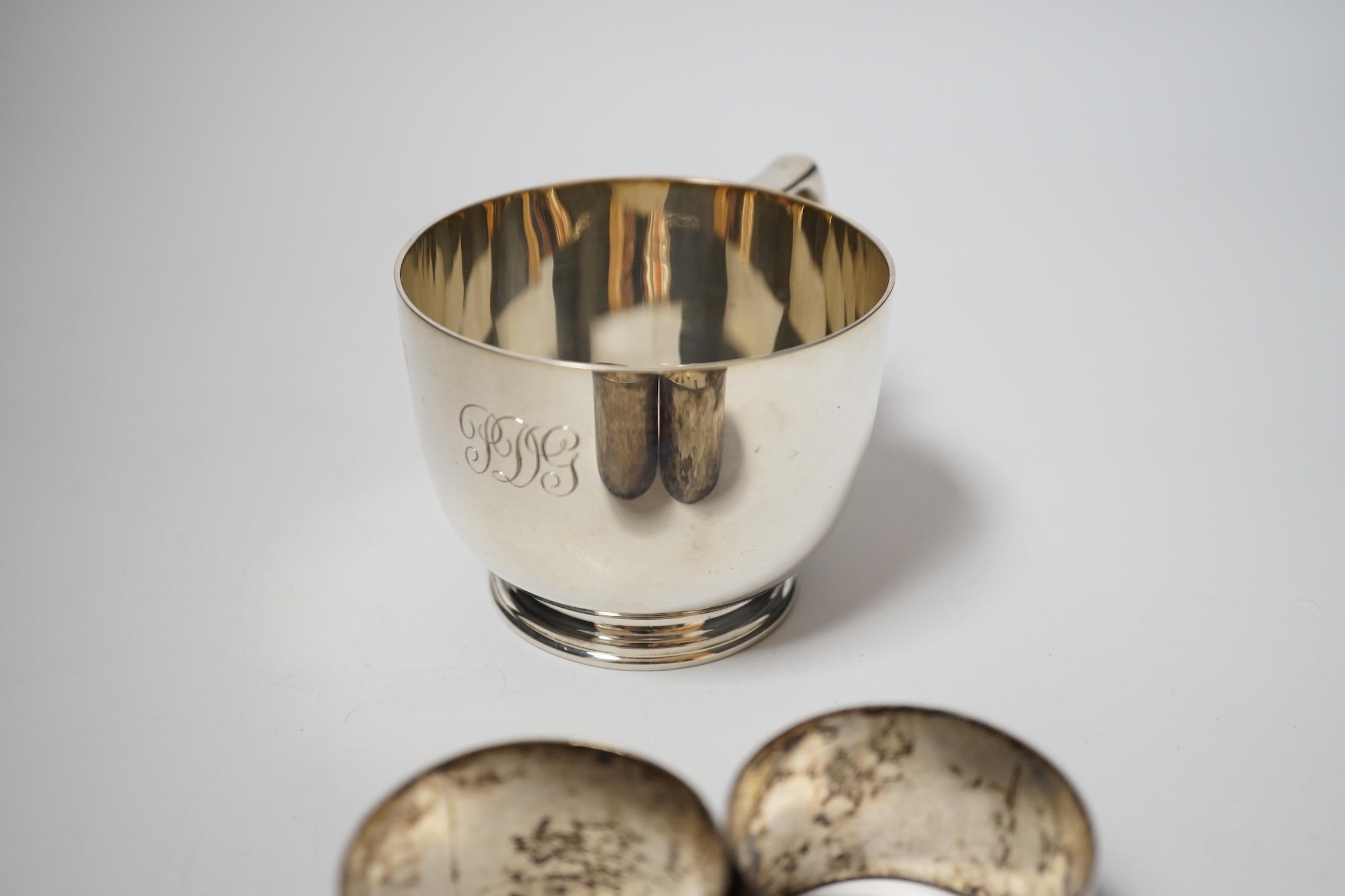 A George V silver cup, with single handle, Searle & Co, London, 1932, height 61mm, together with a pair of late Victorian silver napkin rings, Charles Edwards, London, 1899, 8oz.